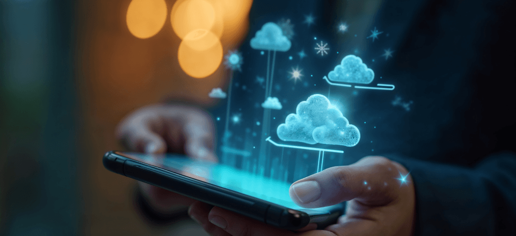 A hand holding a smartphone with cloud icons rising from its screen
